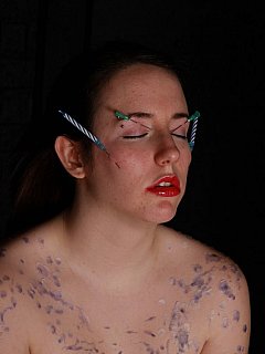 Submissive slut is having her entire face pierced with niddles holding burning candles
