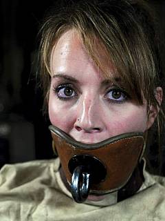 Mental institution restraints: gagged girl is wearing classic straightjacket