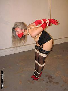 MILF lady is greeting you in corset, black stockings and in strappado bondage pose