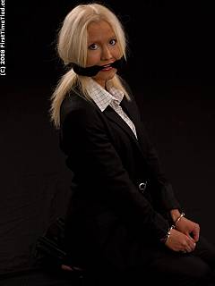 A girl in a business suit is handcuffed and gagged with scarf