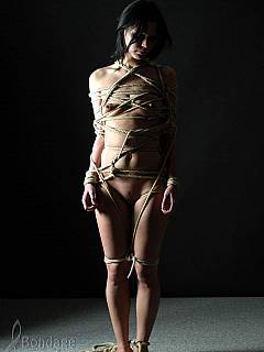 Nude poser is wrapped in ropes and posing alone in the dark