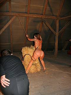 Tied girl is put on top of the haystack and tortured with two whips