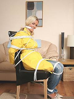 Fully-clothed bondage: woman in raincoat and jeans is tied to chair