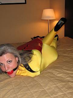 Mature bondagfe slut is dressed in bright yellow satin catsuit