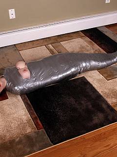 Duct tape mummification: redhead is bound from top to bottom with only her head and big boobs left visible