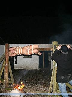 Someone's wife is being cooked: tied naked to the post, gagged with onion and rotated over the open flame