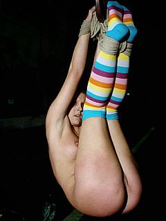 Whipping doll is hanging like a piece of meat wearing nothing but colourful socks