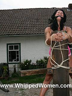 Captive woman is tied to the BDSM rack: whipped and interrogated by two officers