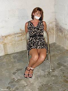 MILF wife is placed into the concrete bunker: tied to chair, tape gagged and looking sexy