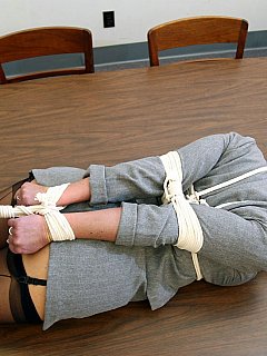 Clothed bondage: sexy office lady is hogtied on the table and having a ball gag in her mouth