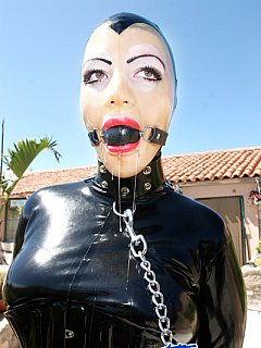 Ball gagged maid is dressed in rubber costume and serving her mistress in the hot sun 