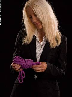 A girl in a business suit is handcuffed and gagged with scarf