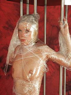 Full body plastic wrapping: teenage beauty is nude and bound spread with lots of tape