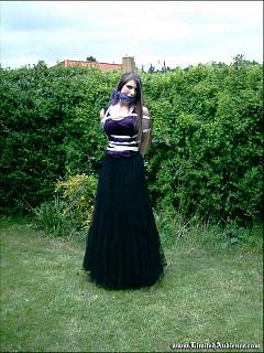 Gothic girl is tied to the wooden post in the backyard