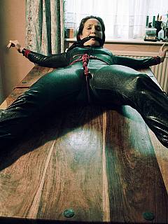 MILF in a black catsuit is tied to table and gagged with scarf