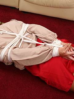 Barefoot redhead is lying on the floor hogtied in her office