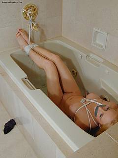 Bound and tape-gagged blond is in the bathtub: slips down a bit and goes under the water with the danger of drowning