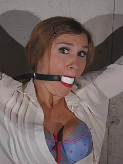 Lovely babe in pink is spread-tied across the wall: she is gagged and her blouse is unbuttoned