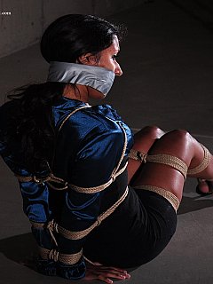 A view of a leggy gal in captivity: wearing mini-dress, high eels and tightly gagged with duct tape